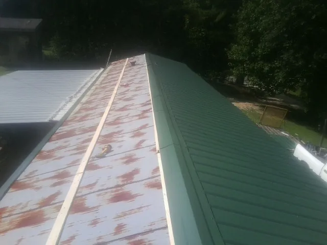Old rusted panels beside newly installed green metal roofing — Wind Damage Roof Repair by Roofing Brothers in Minneapolis