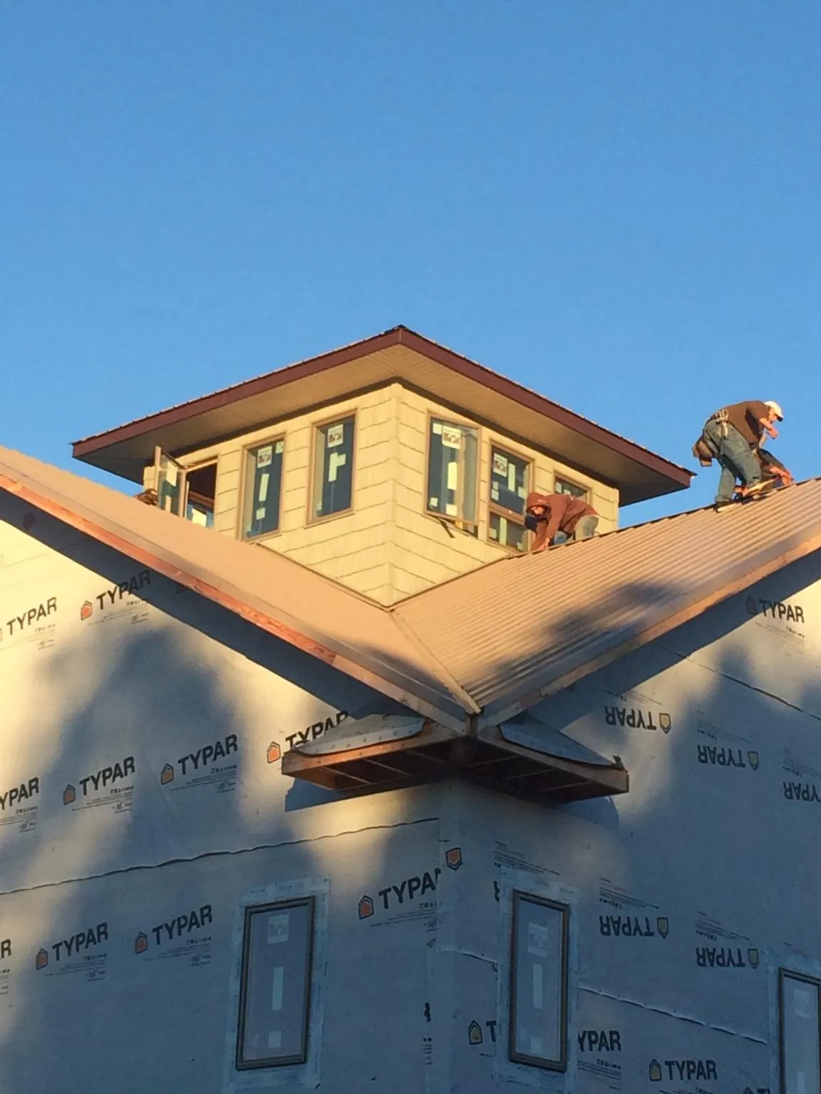 Roofers working around a rooftop cupola on a new metal roof at sunset — Roof Waterproofing in Minneapolis by Roofing Brothers